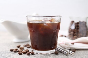 Tasty iced coffee and beans on light table, closeup