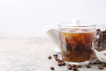 Tasty iced coffee with milk and beans on light table, closeup. Space for text