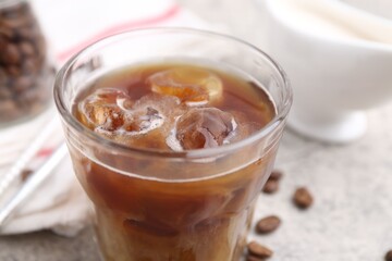 Tasty iced coffee with milk and beans on light table, closeup