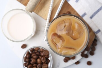 Tasty iced coffee with milk and beans on white table, flat lay