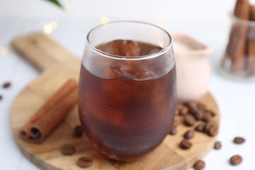 Tasty iced coffee in glass and beans on white table, closeup