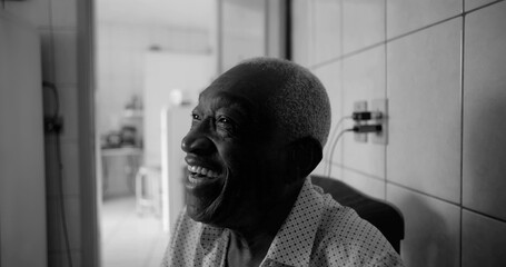 Elderly man of African descent laughing joyfully in a tiled kitchen, black and white portrait...