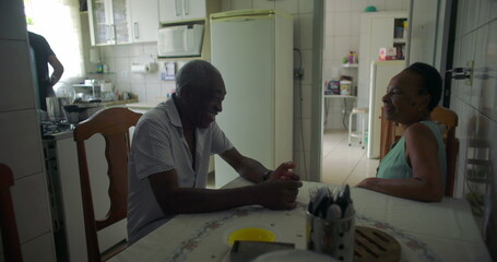 Elderly couple of African descent having a conversation at a dining table, intimate family...