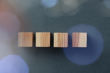 Blank wooden cubes on grey background, flat lay. Bokeh effect