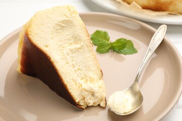 Piece of delicious Basque cheesecake with mint on table, closeup