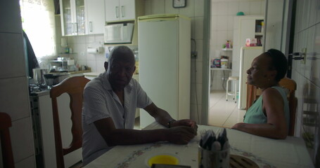 Elderly couple of African descent having a conversation at a dining table, intimate family...