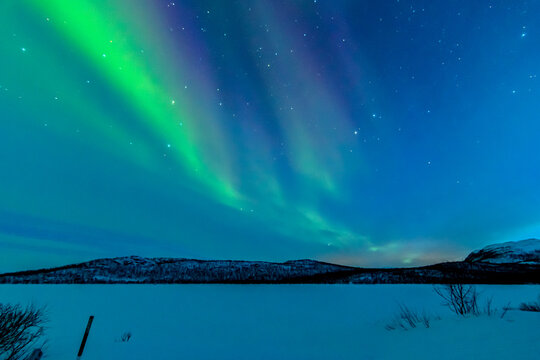 Leuchtende Nordlichter. Gr&uuml;n-violette Aurora Borealis tanzt &uuml;ber Landschaft und Himmel.