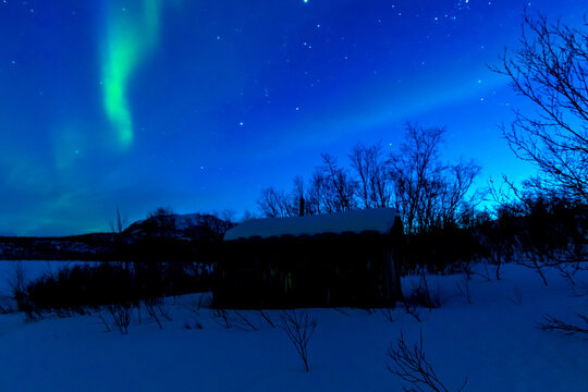 Leuchtende Nordlichter. Gr&uuml;n-violette Aurora Borealis tanzt &uuml;ber Landschaft und Himmel.