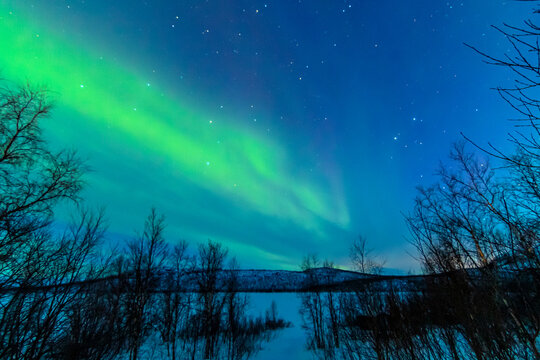 Leuchtende Nordlichter. Gr&uuml;n-violette Aurora Borealis tanzt &uuml;ber Landschaft und Himmel.