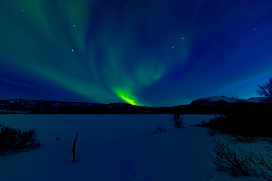 Leuchtende Nordlichter. Gr&uuml;n-violette Aurora Borealis tanzt &uuml;ber Landschaft und Himmel.