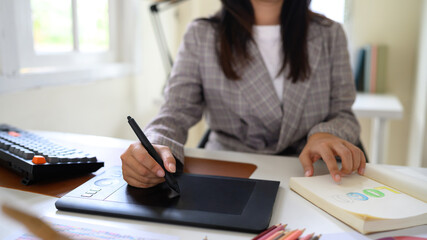 Cropped shot graphic designer working on creative desk computer while using graphic tablet at desk