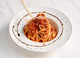 Classic Italian Spaghetti Bolognese with Parmesan Chesse, Meat Sauce and Breadstick on White Plate isolated on marble background top view of Italian cousin