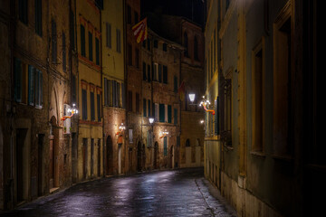 Empty wet Italian street at night, glowing lamps and old colorful facades