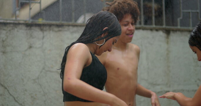 Teenagers holding hands and laughing in the rain, celebrating friendship, unity, and youthful vibrancy in a carefree and joyful outdoor experience