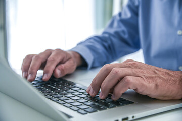 Closeup man hands typing on computer keyboard. Businessman using laptop at home. Office workplace