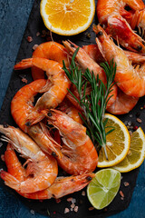 Freshly frozen shrimp, with lemon and rosemary, on black slate, close-up, top view, no people