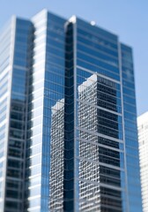 Modern glass skyscraper reflecting high-rise building on clear sky day