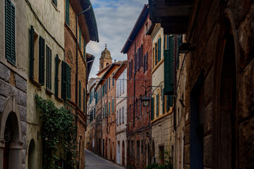 Historic narrow street with colorful facades, green shutters and church tower, Tuscany