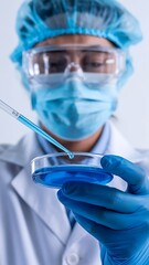 Scientist adding blue liquid to petri dish with pipette laboratory research