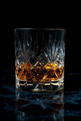 Lowball whisky glass in dark studio environment on dark marble table