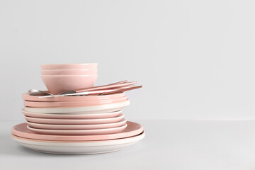 Clean plates with bowls and cutlery on white background