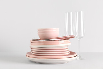 Clean glasses with plates, bowls and cutlery on white background