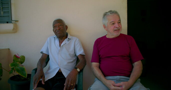 Elderly African American man smiling and chatting with a friend on outdoor patio, enjoying a friendly and relaxed social moment - Powered by Adobe