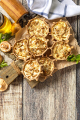 Rustic mushroom tartlets on wooden cutting board perfect for  appetizers. Top view flat lay.