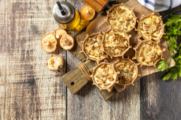 Rustic mushroom tartlets on wooden cutting board perfect for  appetizers. Top view flat lay background. Copy space.