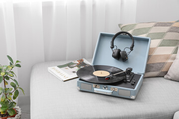Record player and headphones on grey sofa in living room