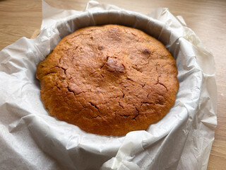 Freshly baked homemade pie in parchment paper on wooden table.