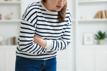 Woman suffering from stomach ache and nausea at home, closeup. Space for text