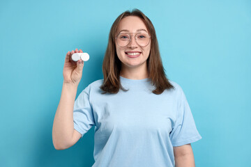 Woman in glasses with contact lenses on light blue background