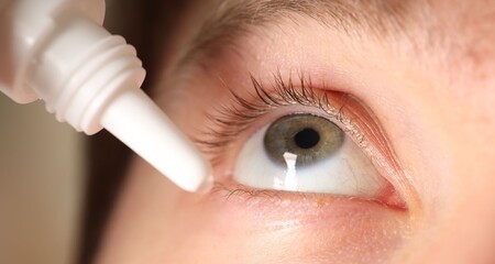 Man applying eye drops on blurred background, closeup
