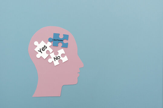 A paper silhouette of a head with puzzles inside, with the words "yes, no, I don't know" on a blue background