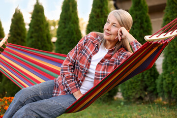 Beautiful senior woman resting in hammock outdoors