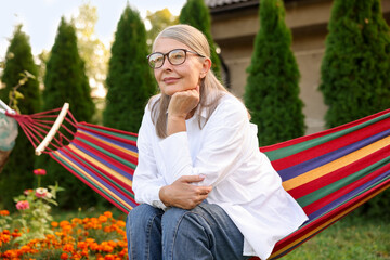 Beautiful senior woman resting in hammock outdoors