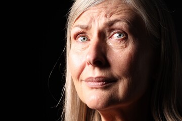 Senior woman crying on black background, closeup. Space for text