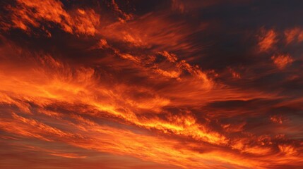 Fototapeta premium A stunning sunset displays brilliant orange and crimson hues across the sky casting a warm glow over the landscape as day turns to night. The clouds create a beautiful dramatic effect.
