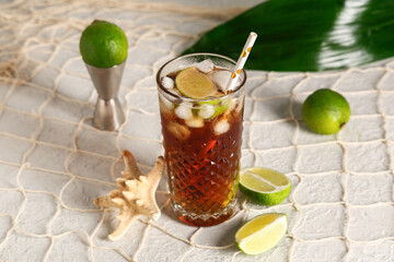 Glass of cold Cuba Libre cocktail with starfish, measure cup and tropical leaf on white background