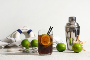 Glass of cold Cuba Libre cocktail with strainer, shaker and starfish on white background