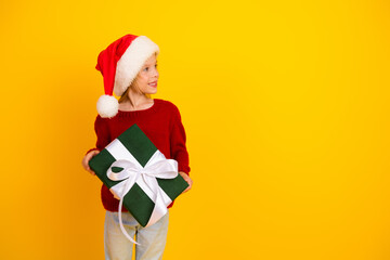 Funny santa hat kid with large gift smiles for christmas celebration and family joy