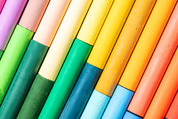 Bright background made of colorful oil pastels arranged in diagonal lines. Close-up of vivid artistic crayons in various shades, symbol of creativity, art and education.