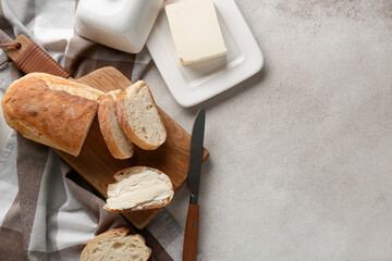 Sliced bread with butter and knife on grey grunge background