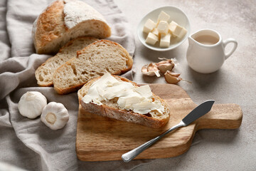 Sliced bread with butter, garlic and jug of cream on grey grunge background