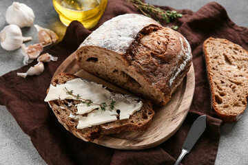 Sliced bread with butter, garlic and thyme on grey grunge background