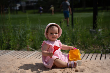 cute baby in pink dress enjoys playtime with sand toys under sunny sky in a park setting, highlighting a joyful outdoor family experience in natural surroundings, lawn, curious, footwear, soft