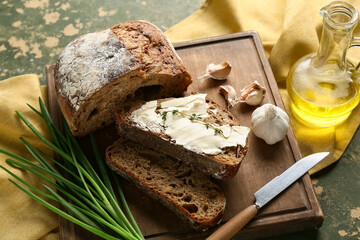Sliced bread with butter, garlic, green onion and jug of oil on green grunge background