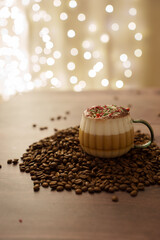 a frothy layered coffee in a glass mug rests on a pile of coffee beans, decorated with festive sprinkles, set against a warm and soft background of glowing bokeh lights, decor, tasteful, indulgence
