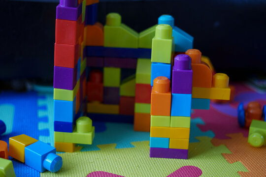 colorful interlocking building blocks set on vibrant foam play mat with blue, green, and red shapes in indoor playroom setting, showcasing creative and imaginative play, background, decor, creative